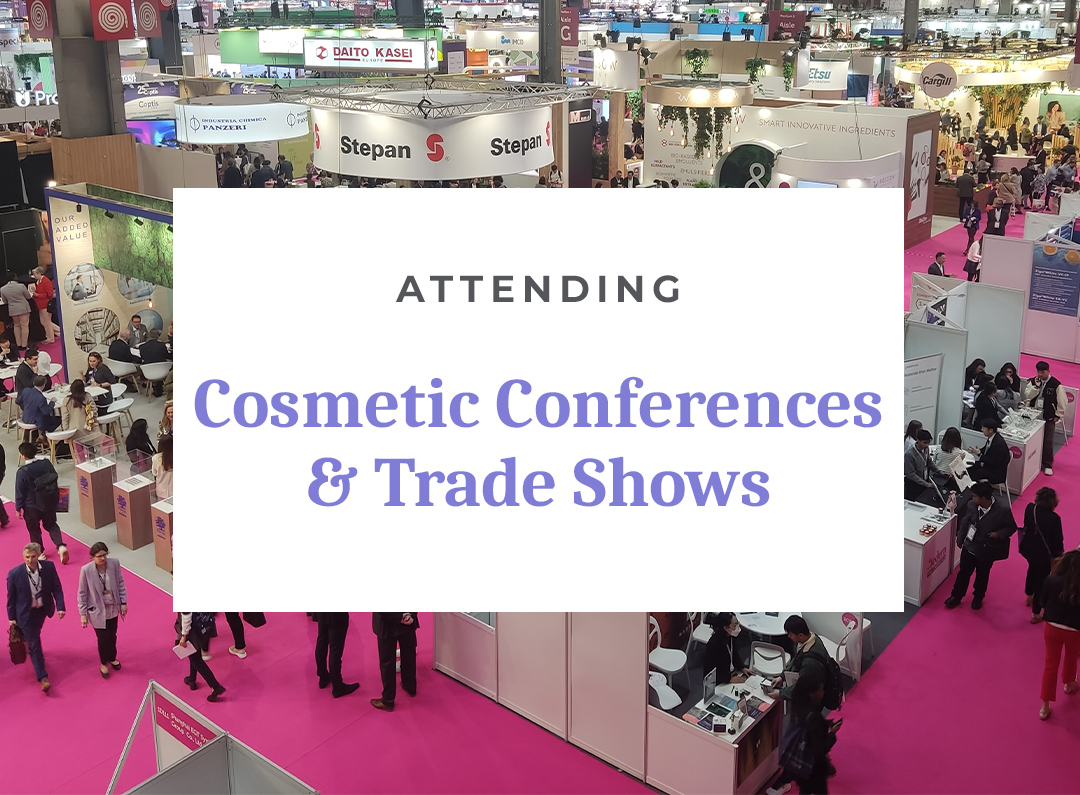 Crowded cosmetic trade show with various booths and attendees.