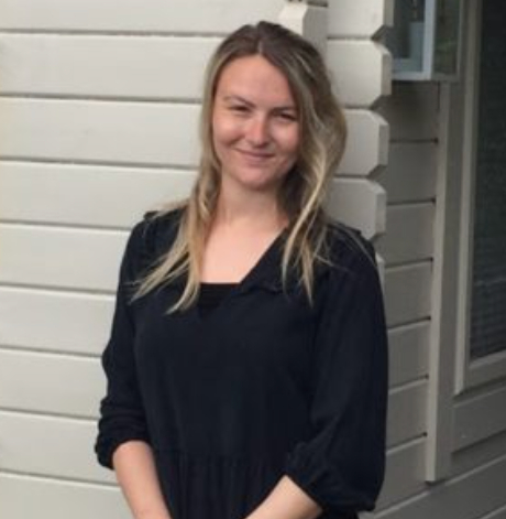 Smiling person standing outside a building.