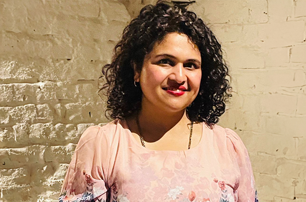 Person smiling in a floral dress indoors.