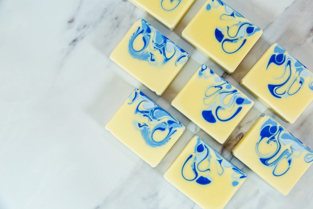 Handmade soap bars with blue swirls on marble.