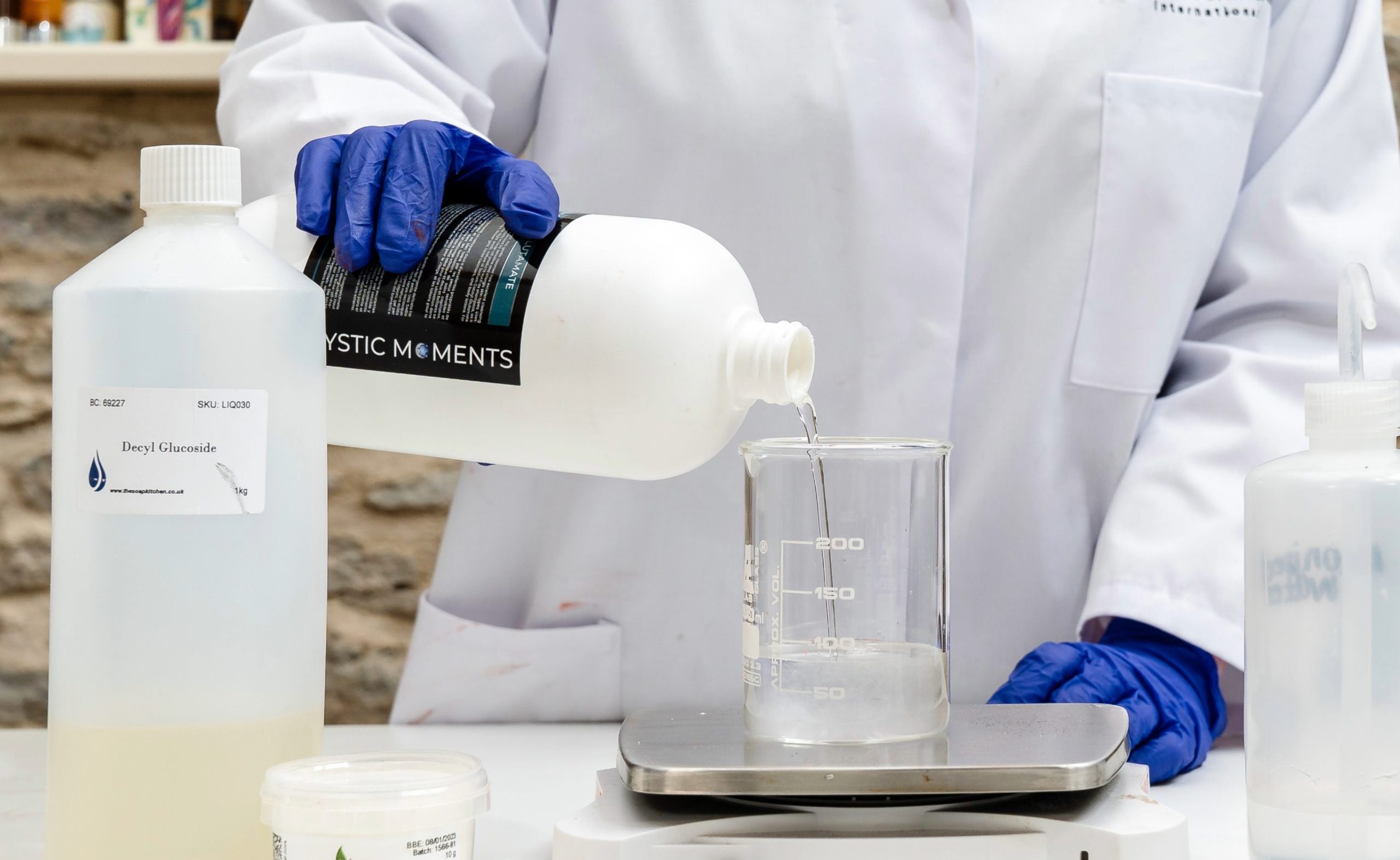 Scientist pouring liquid into a beaker on scale.