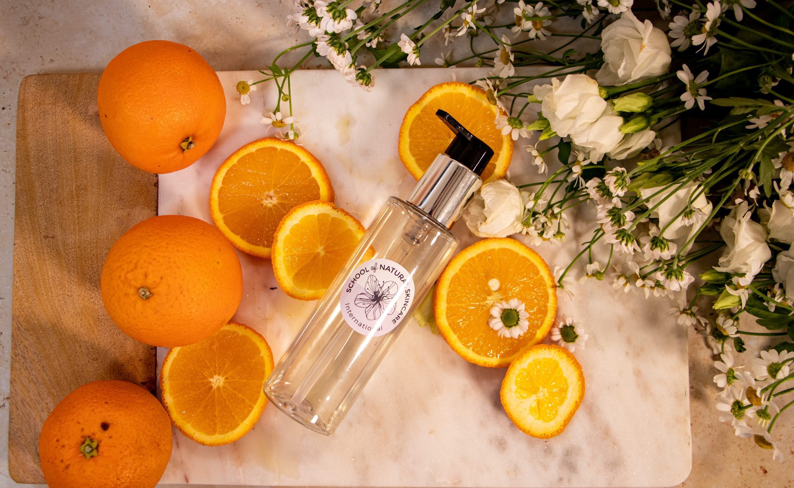 Oranges and flowers with a skincare bottle